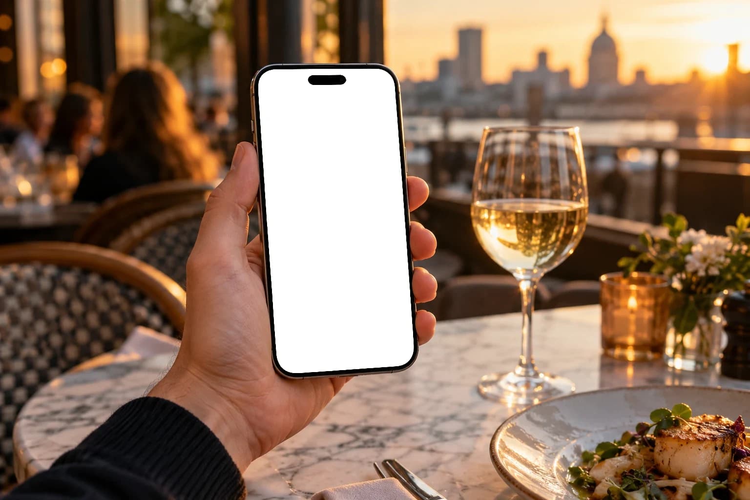 A guest paying the bill with OpenRate on a phone at a restaurant terrace at sunset